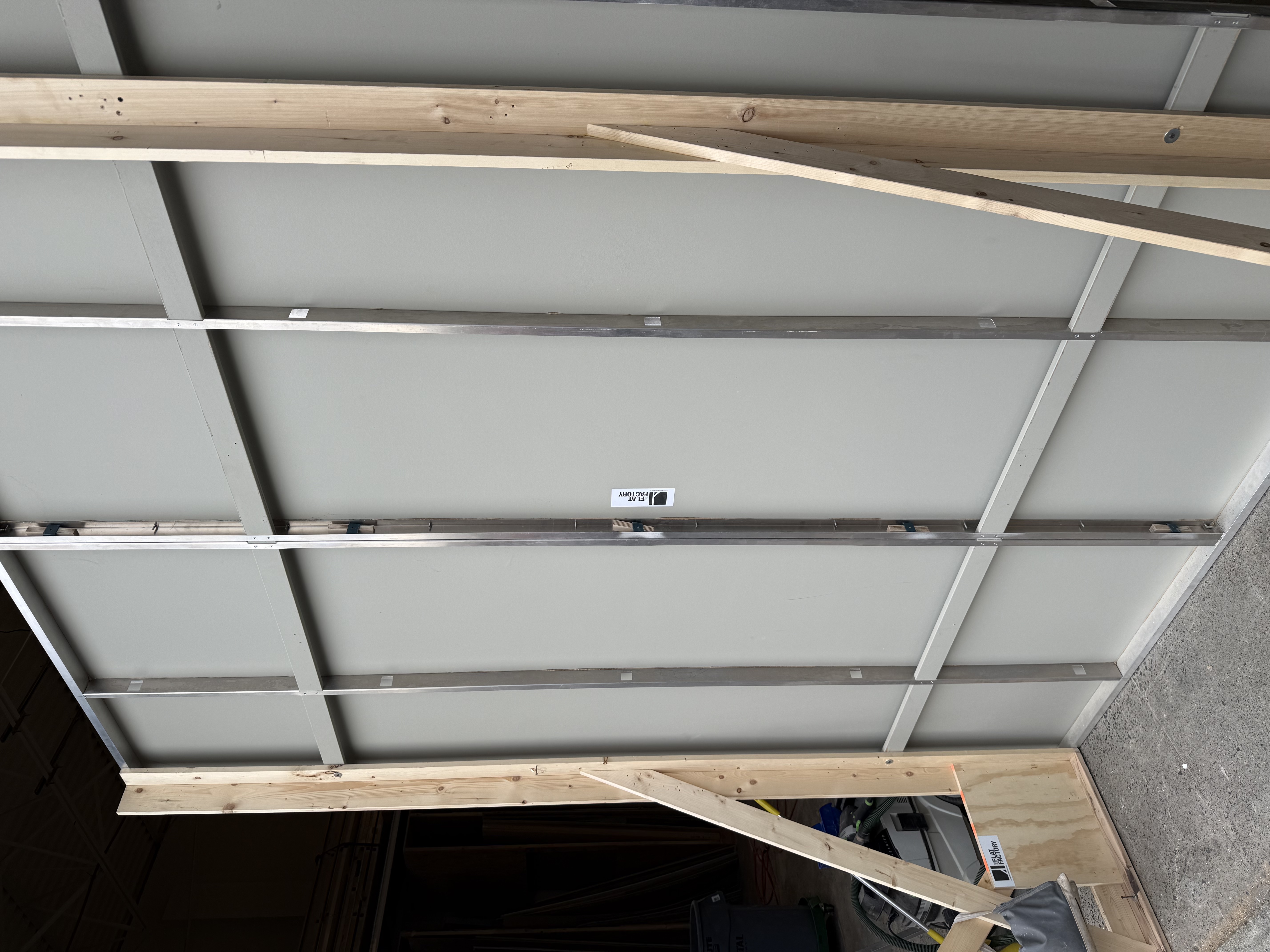 Side view of modular indoor-outdoor wall panel showing metal frame and wooden braces in workshop