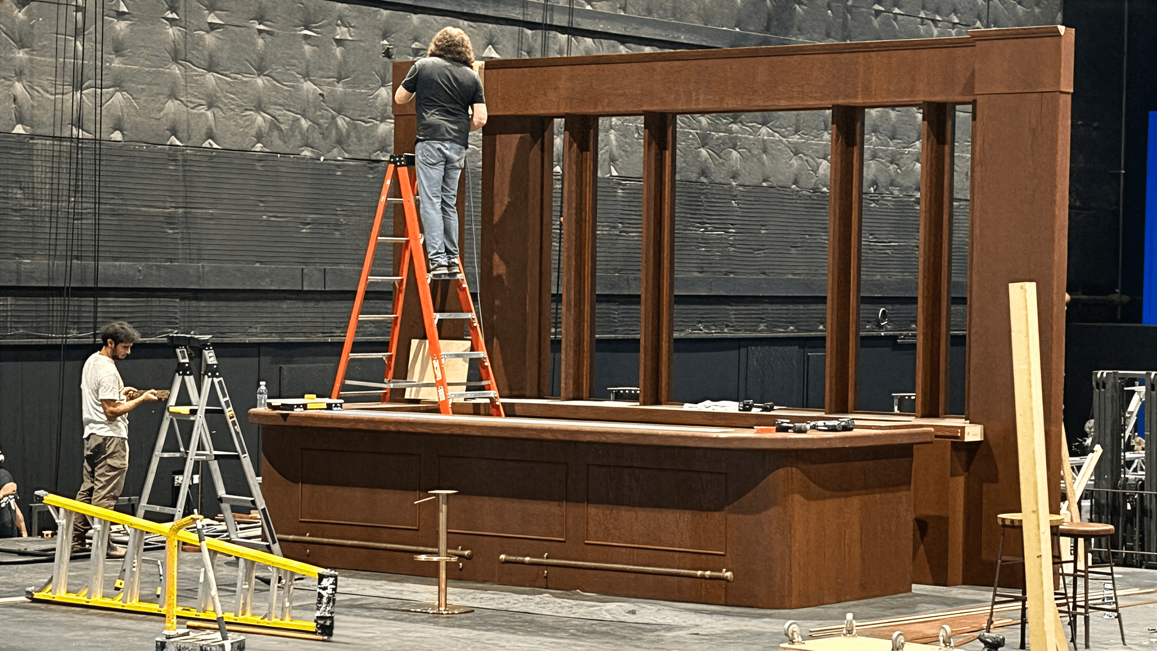 Membre de l'équipe sur une échelle construisant la structure d'un décor de bar en bois sur un plateau pour une publicité Captain Morgan