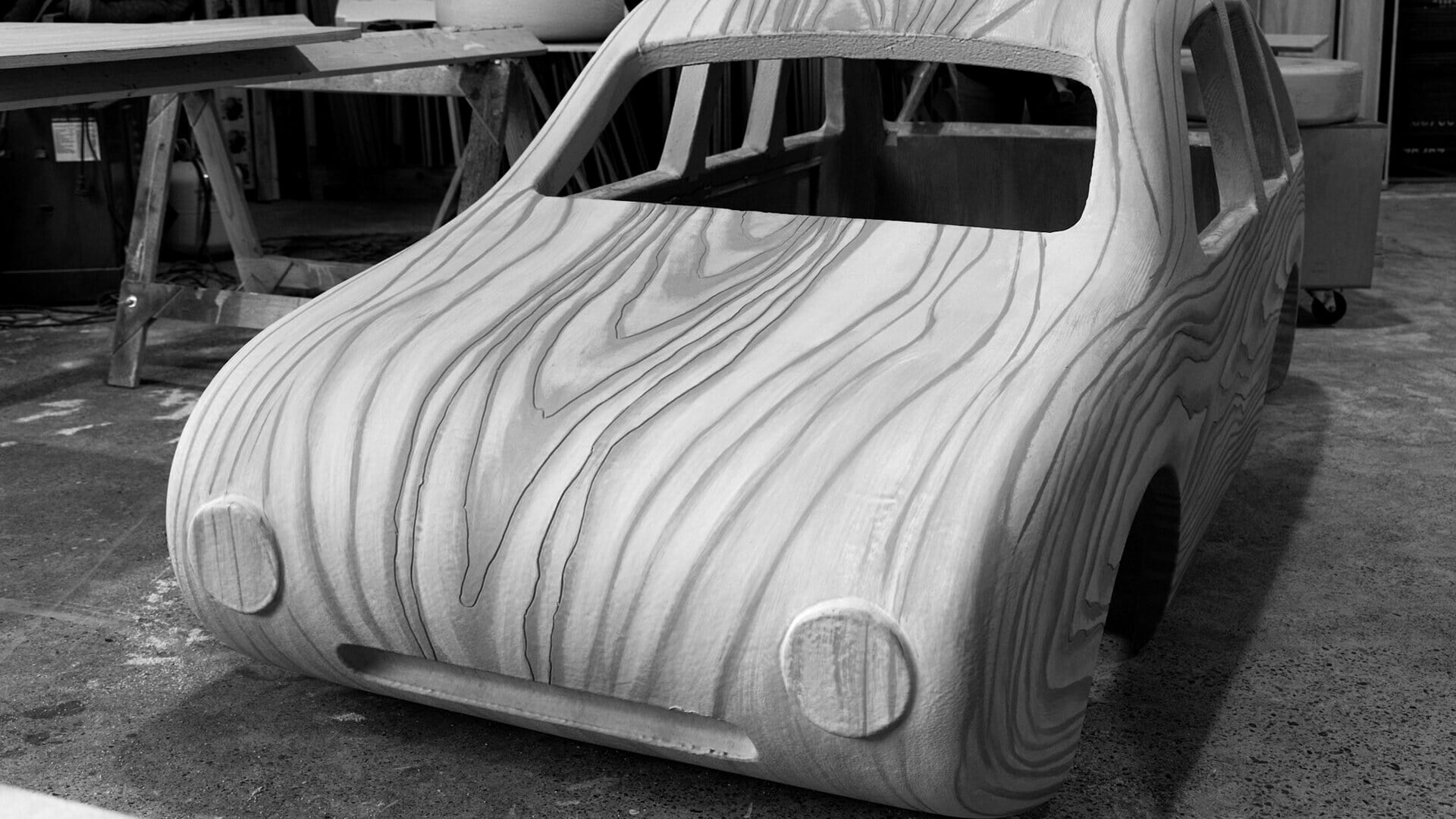 Black-and-white front view of a life-size wooden toy car built for the KIA Seltos commercial.