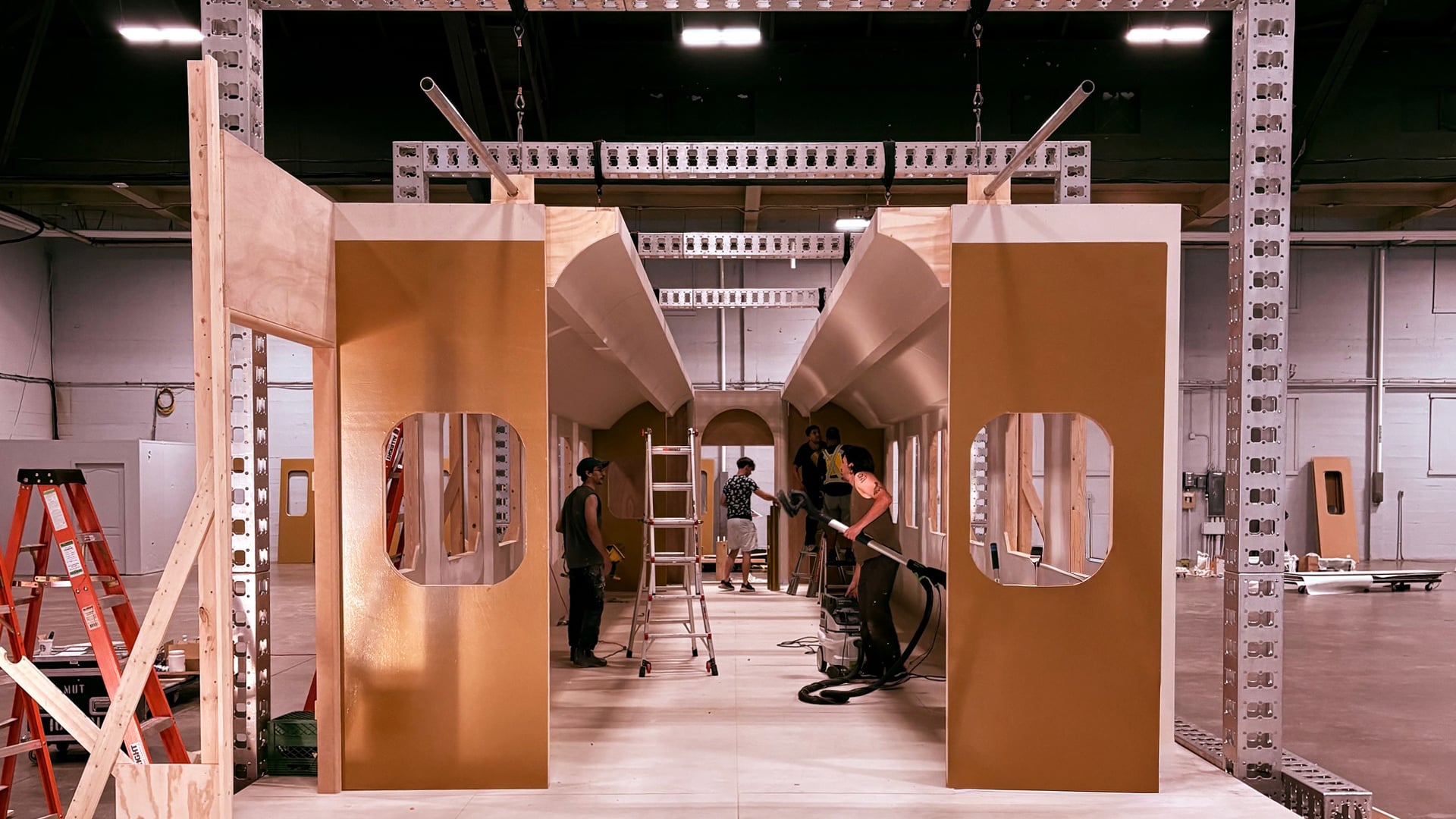 Front entrance view of train cabin set under construction with gold-painted walls and oval windows in warehouse for MGM Grand