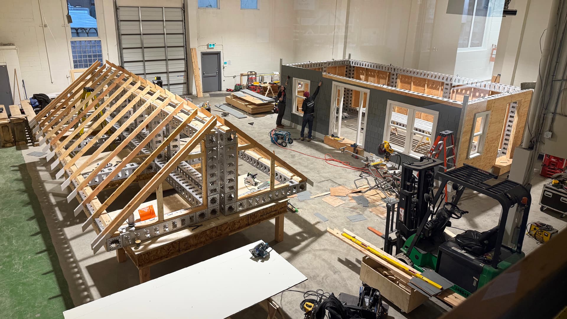 Workshop overview showing roof truss assembly and cottage wall construction for Nissan commercial